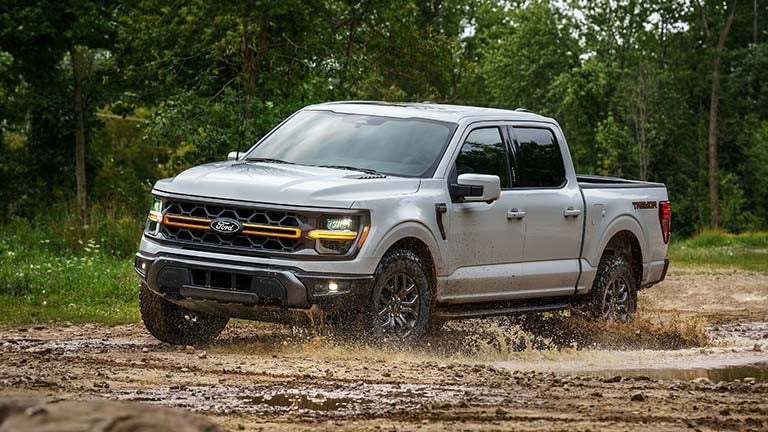 2025 Ford F-150® pickup driving through mud.