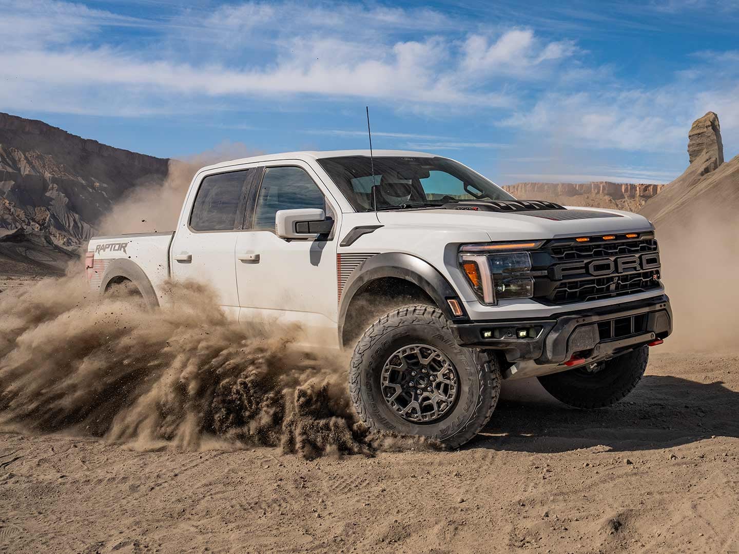 2025 Ford F-150® Raptor R® pickup in Carbonized Gray kicking up a cloud of dust in the desert