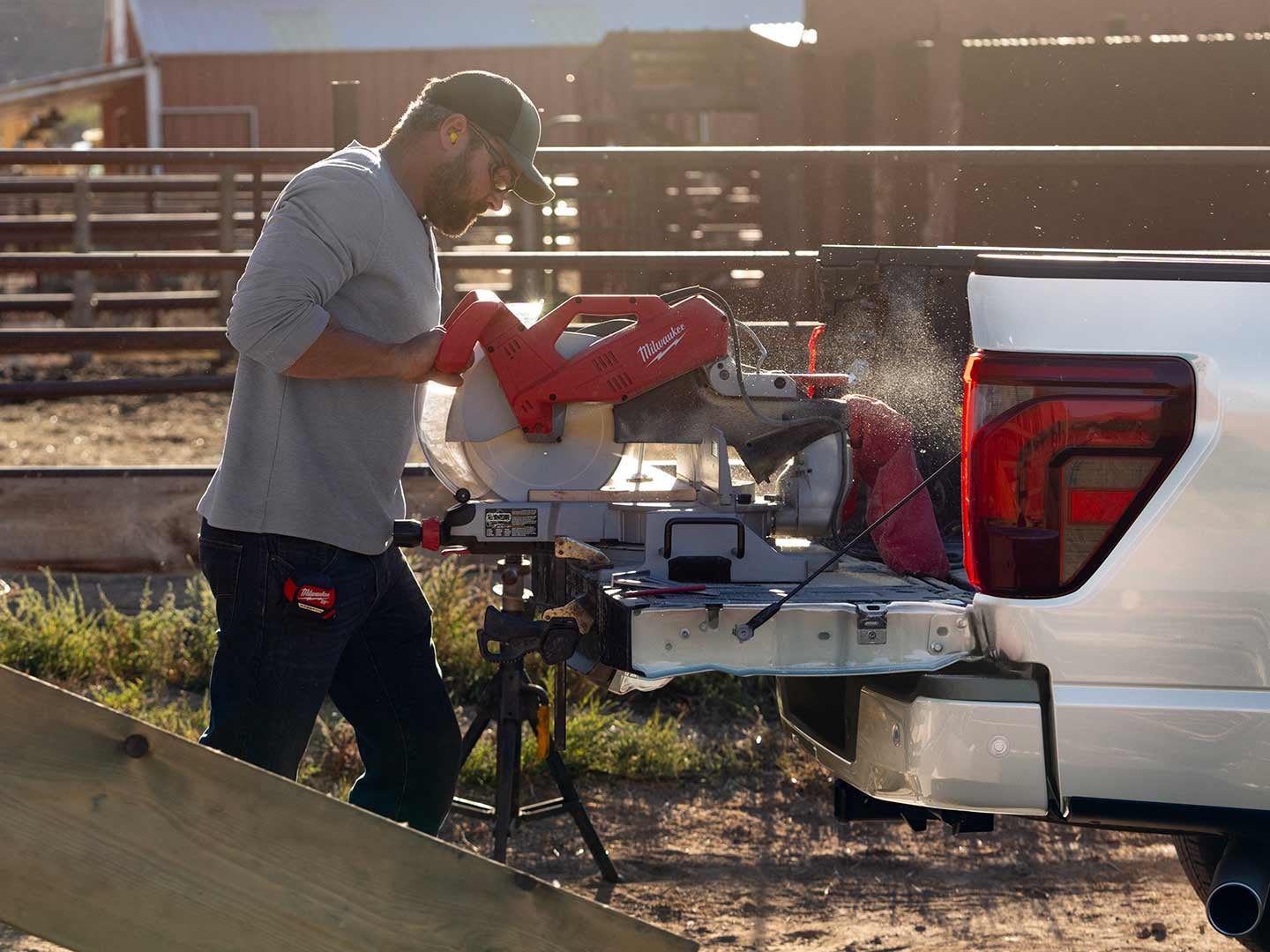 Man using a miter saw on the tailgate while plugged into the Pro Power Onboard feature